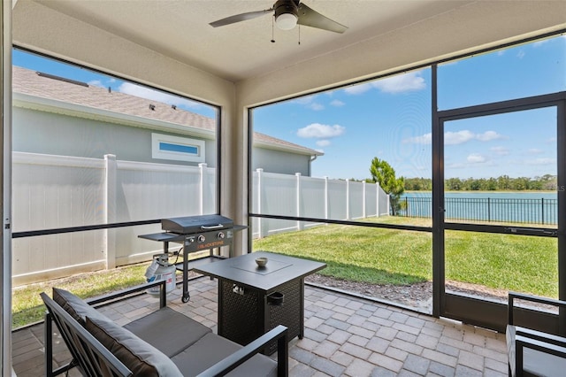 sunroom / solarium featuring a water view and ceiling fan