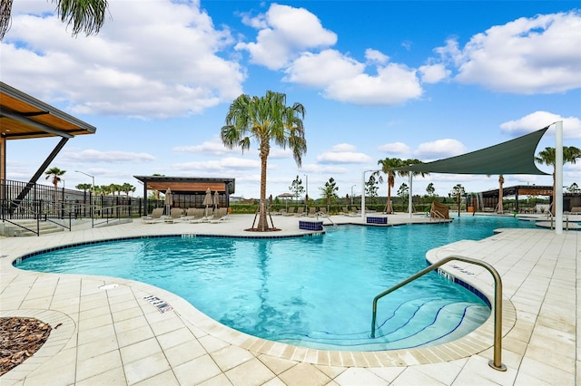 community pool with a patio and fence