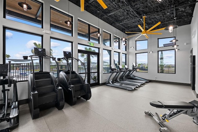 workout area featuring baseboards and a high ceiling