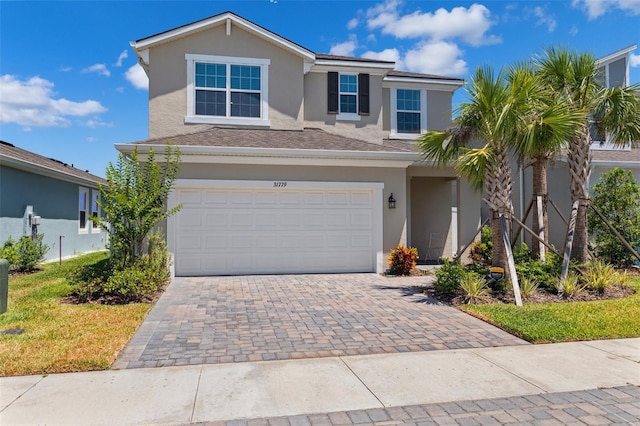 traditional-style home featuring stucco siding, decorative driveway, and a garage