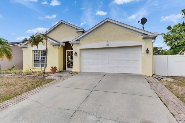 ranch-style home featuring stucco siding, driveway, an attached garage, and fence