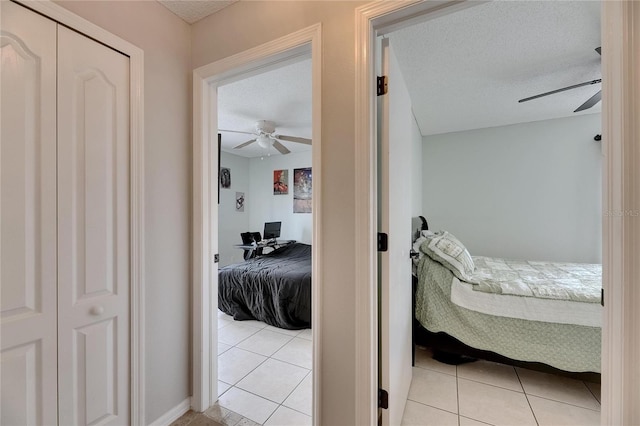 bedroom featuring light tile patterned flooring, a ceiling fan, and a textured ceiling