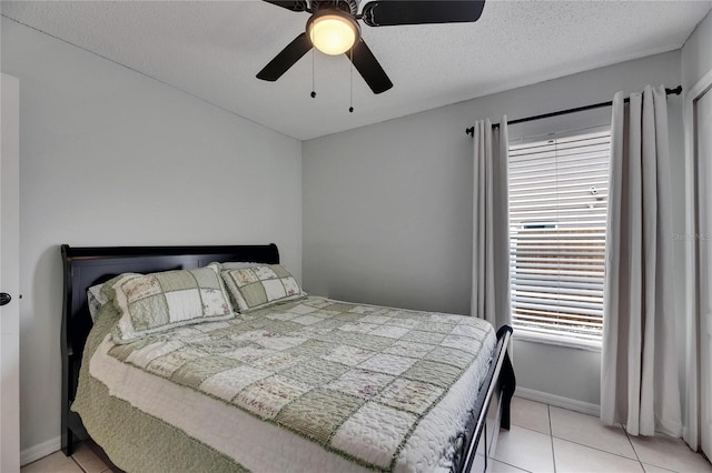 bedroom featuring light tile patterned floors, ceiling fan, baseboards, and a textured ceiling