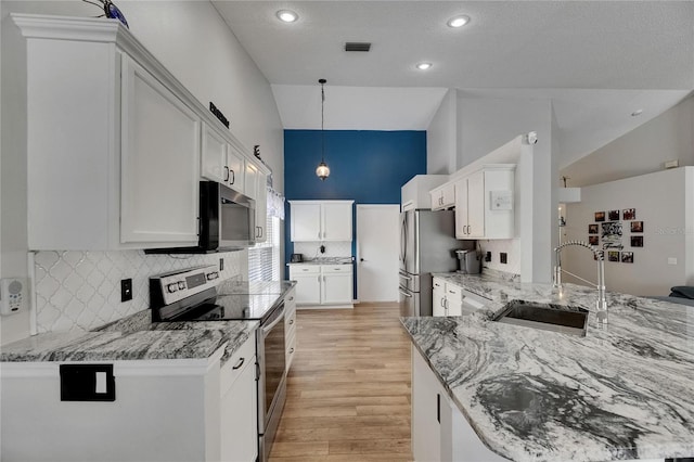 kitchen featuring stainless steel appliances, a sink, light wood-style floors, decorative backsplash, and light stone counters