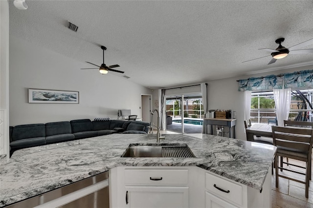 kitchen featuring ceiling fan, a sink, open floor plan, a textured ceiling, and lofted ceiling