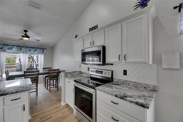 kitchen with stainless steel appliances, backsplash, white cabinetry, a textured ceiling, and ceiling fan