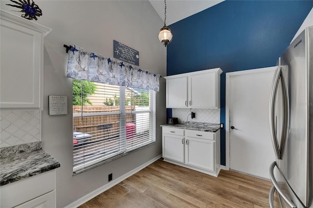 kitchen with freestanding refrigerator, tasteful backsplash, light wood-style floors, white cabinetry, and lofted ceiling