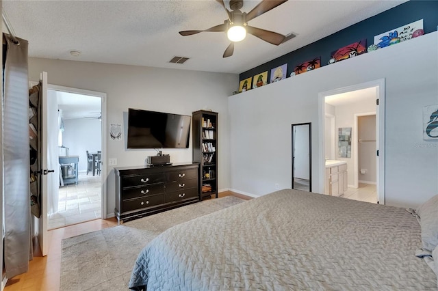 bedroom featuring vaulted ceiling, ceiling fan, baseboards, and ensuite bath