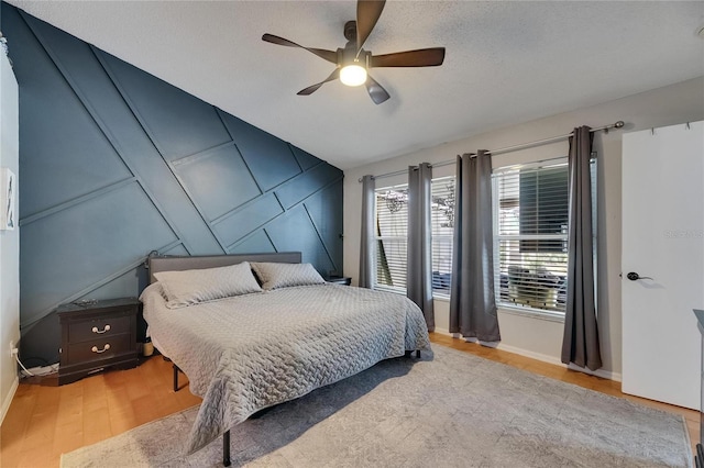 bedroom featuring baseboards, wood finished floors, and a ceiling fan
