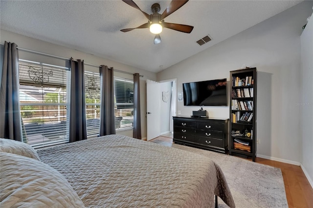 bedroom with vaulted ceiling, baseboards, wood finished floors, a ceiling fan, and a textured ceiling