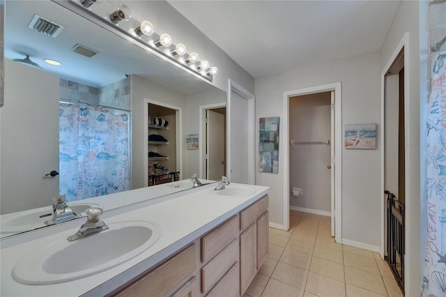 bathroom with tile patterned floors, double vanity, a walk in closet, curtained shower, and baseboards