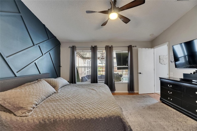 bedroom featuring multiple windows, a textured ceiling, baseboards, lofted ceiling, and a ceiling fan