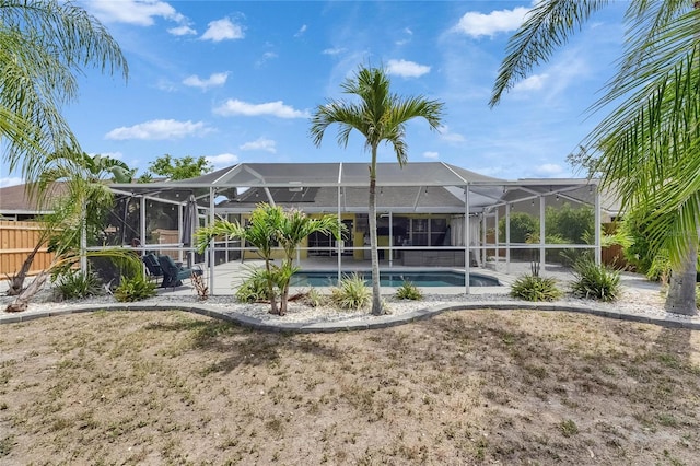 rear view of house with an outdoor pool, a lanai, fence, and a patio