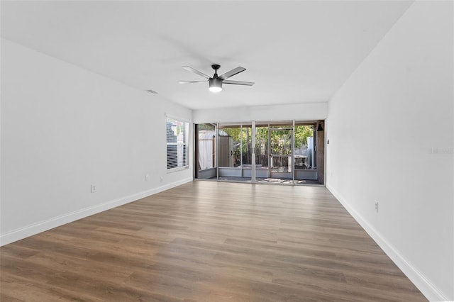 empty room featuring baseboards, wood finished floors, ceiling fan, and a healthy amount of sunlight