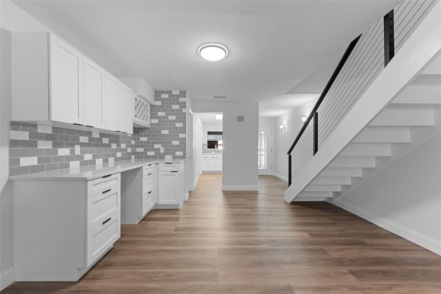 kitchen with decorative backsplash, light countertops, baseboards, and white cabinetry