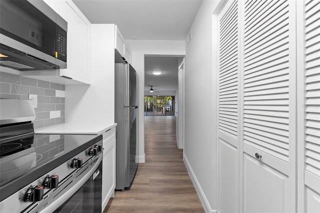 kitchen featuring tasteful backsplash, wood finished floors, stainless steel appliances, light countertops, and white cabinetry