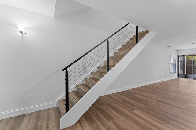 staircase featuring baseboards and wood finished floors