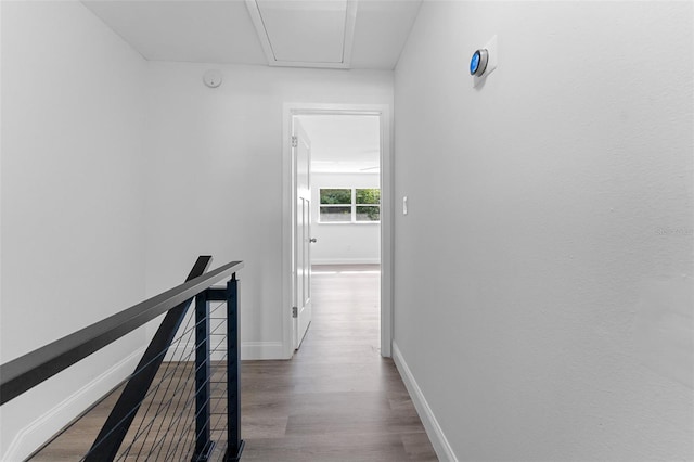 corridor with baseboards, wood finished floors, and an upstairs landing