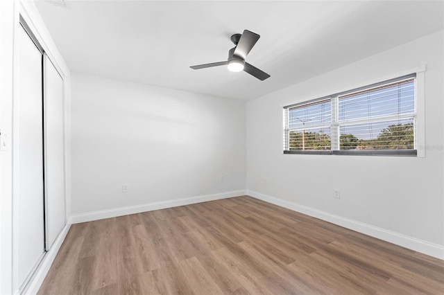 unfurnished bedroom with light wood-style flooring, baseboards, a closet, and ceiling fan