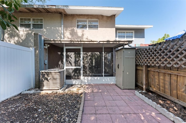 back of house with a fenced backyard, cooling unit, a sunroom, a patio, and stucco siding