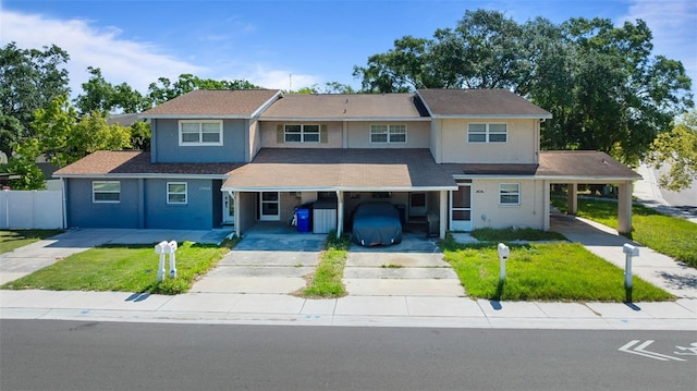 view of front of house featuring a front yard, driveway, a carport, and stucco siding