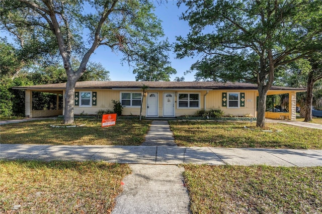 ranch-style house with driveway, a front lawn, and a carport