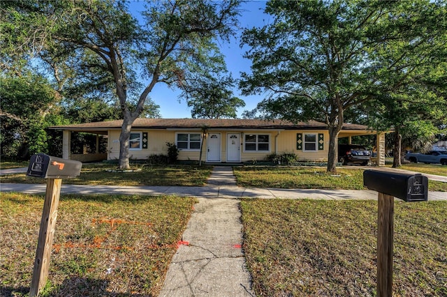 ranch-style home featuring driveway, a front yard, and an attached carport