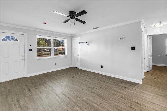 unfurnished living room with wood finished floors, a ceiling fan, visible vents, baseboards, and ornamental molding
