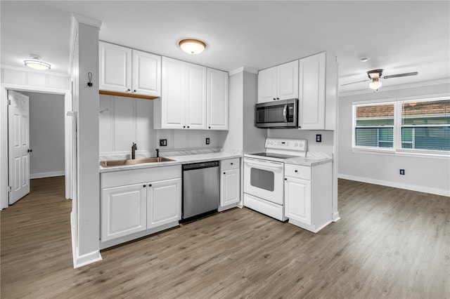 kitchen with a sink, ornamental molding, stainless steel appliances, and light wood-style flooring