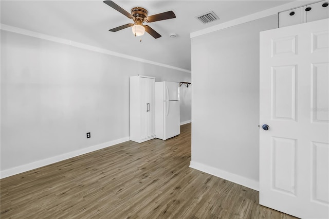 empty room featuring baseboards, a ceiling fan, visible vents, and wood finished floors