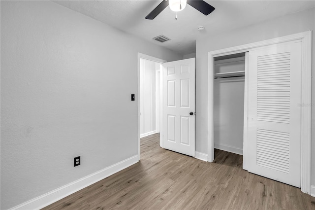 unfurnished bedroom featuring a closet, wood finished floors, visible vents, a ceiling fan, and baseboards