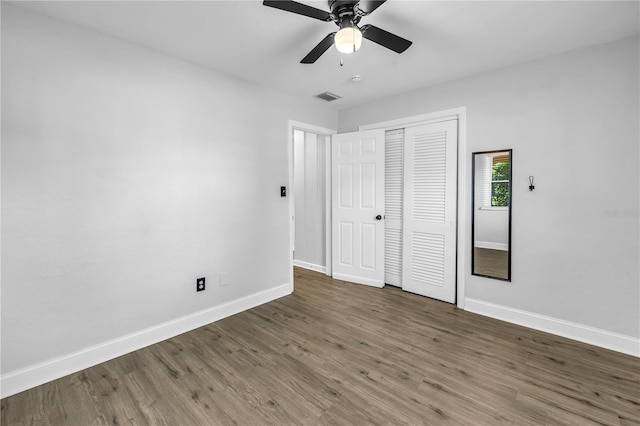 unfurnished bedroom with baseboards, a closet, visible vents, and wood finished floors