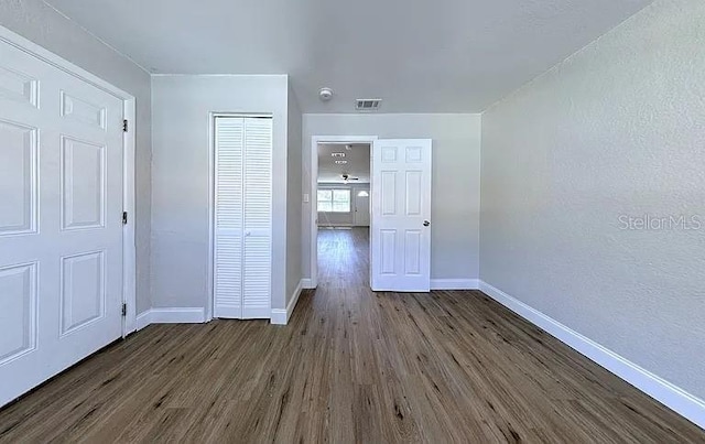 unfurnished bedroom featuring baseboards, dark wood-type flooring, and visible vents