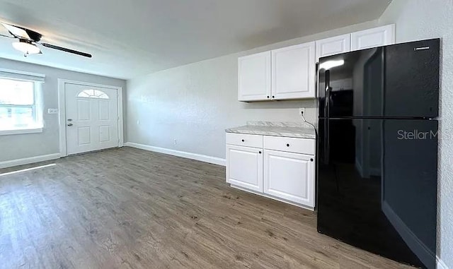 kitchen featuring freestanding refrigerator, white cabinetry, and wood finished floors