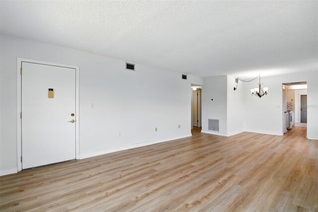 unfurnished living room featuring a chandelier, visible vents, and light wood-style flooring