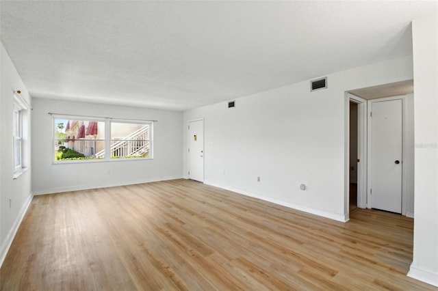unfurnished living room featuring visible vents, light wood-style flooring, and baseboards
