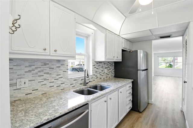kitchen with white cabinetry, stainless steel appliances, light wood finished floors, and a sink