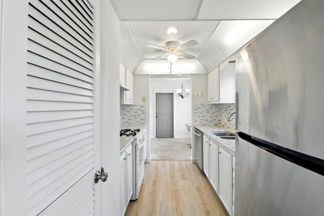 kitchen featuring tasteful backsplash, stainless steel appliances, white cabinets, and ceiling fan with notable chandelier