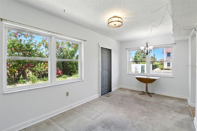 unfurnished dining area with a textured ceiling, baseboards, a chandelier, and carpet floors