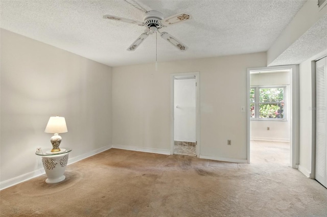 carpeted empty room with a textured ceiling, ceiling fan, and baseboards