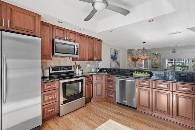 936 Pinellas Bayway S Unit T-5, Tierra Verde, FL 33715 - kitchen featuring a ceiling fan, a sink, decorative backsplash, light wood-style floors, and appliances with stainless steel finishes