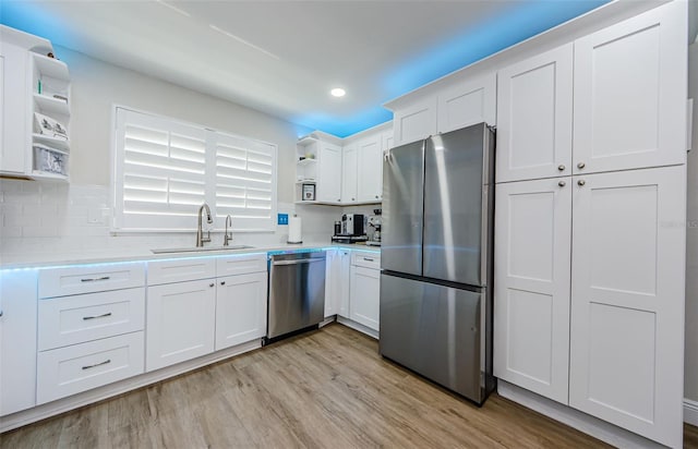 kitchen with open shelves, light wood-style floors, appliances with stainless steel finishes, white cabinets, and a sink