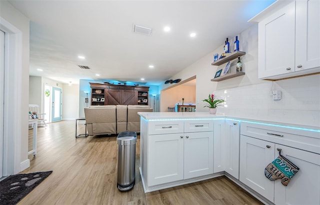 kitchen featuring light wood-style floors, visible vents, backsplash, a peninsula, and open floor plan