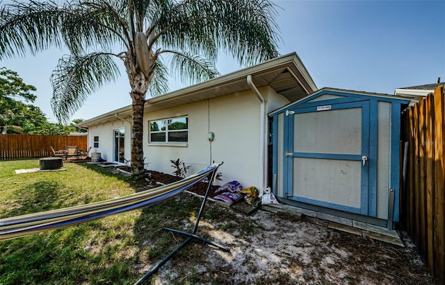view of side of property with fence, an outbuilding, a storage shed, a lawn, and stucco siding