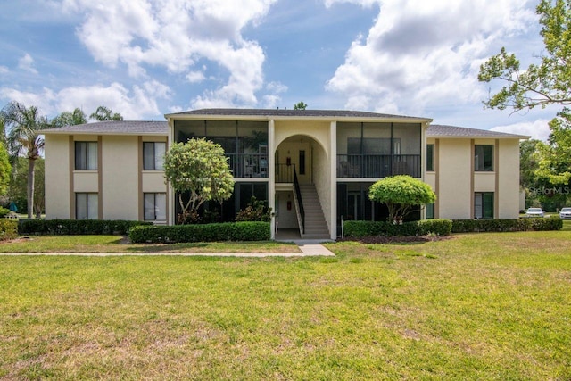 1400 Pine Glen Ln Unit B2, Tarpon Springs, FL 34688 - view of front facade with stucco siding, stairway, a sunroom, and a front yard