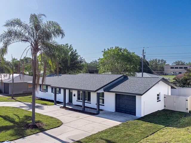ranch-style house featuring a front lawn, driveway, roof with shingles, and a garage
