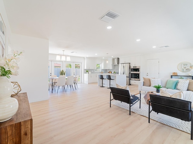 living room featuring french doors, visible vents, recessed lighting, and light wood-style floors