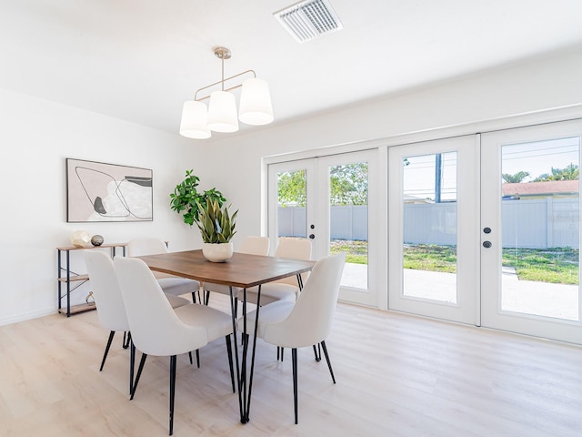 dining space with light wood-style flooring, visible vents, baseboards, and french doors