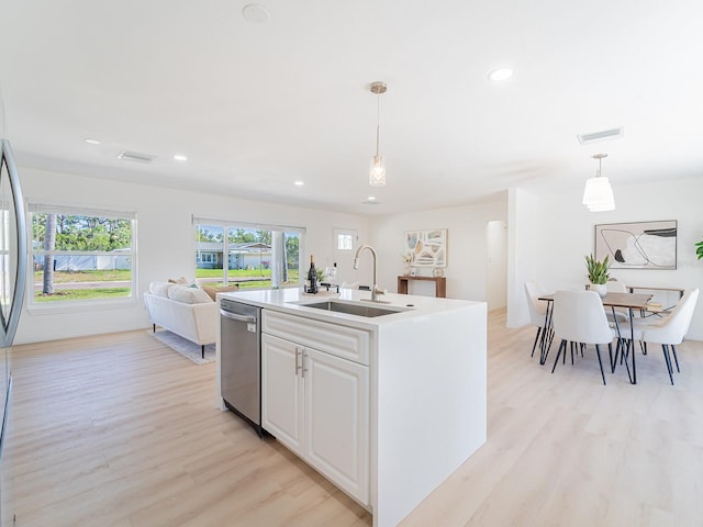 kitchen with stainless steel dishwasher, visible vents, a sink, and light wood-style floors