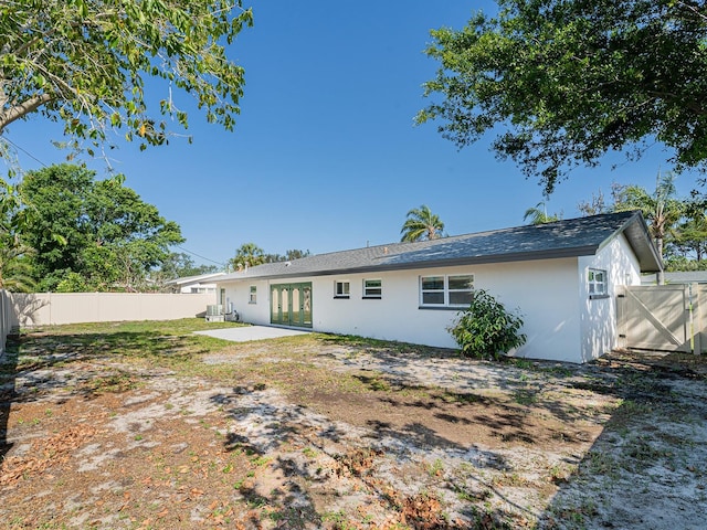 rear view of house with stucco siding, central AC unit, a patio, and a fenced backyard